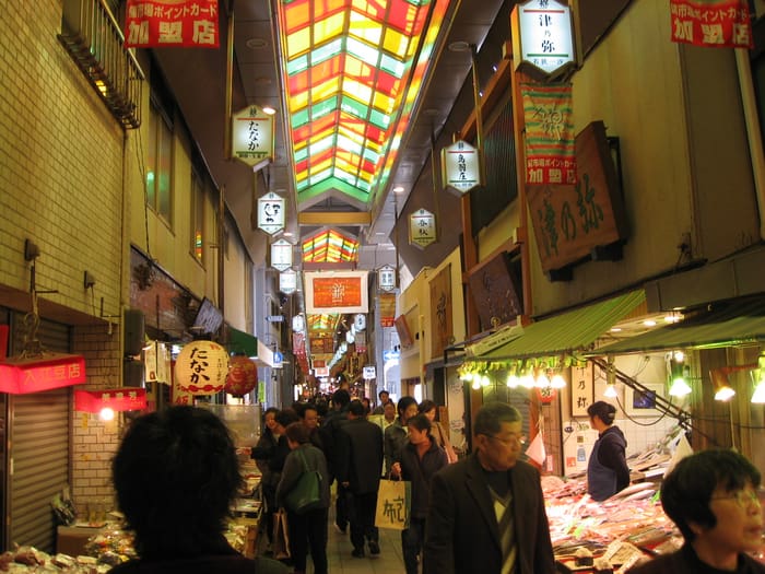 Des passants sous la verrière colorée de la galerie du marché Nishiki
